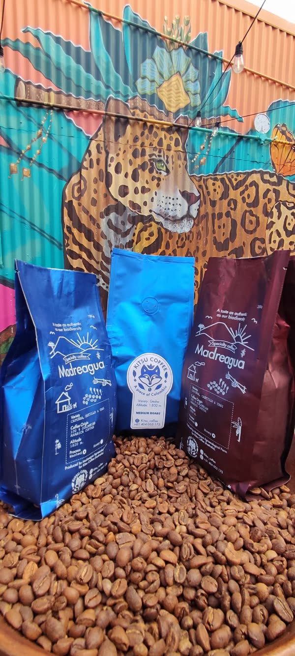 A bag of Kitsu Coffee on a bed of roasted beans in Australia, in front of a jaguar mural