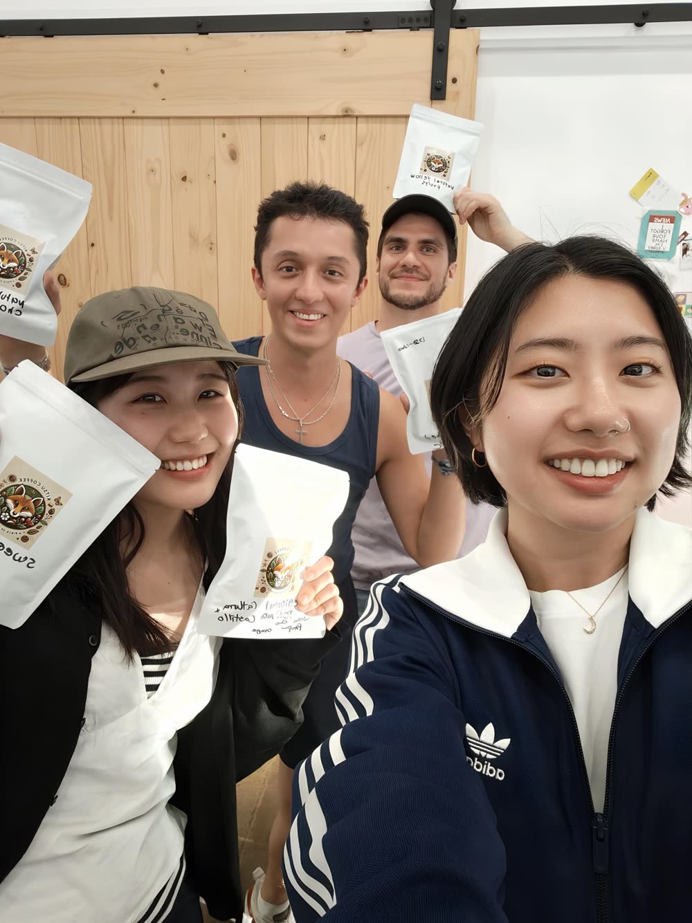 Nicolás with barista friends in Australia holding bags of Kitsu Coffee